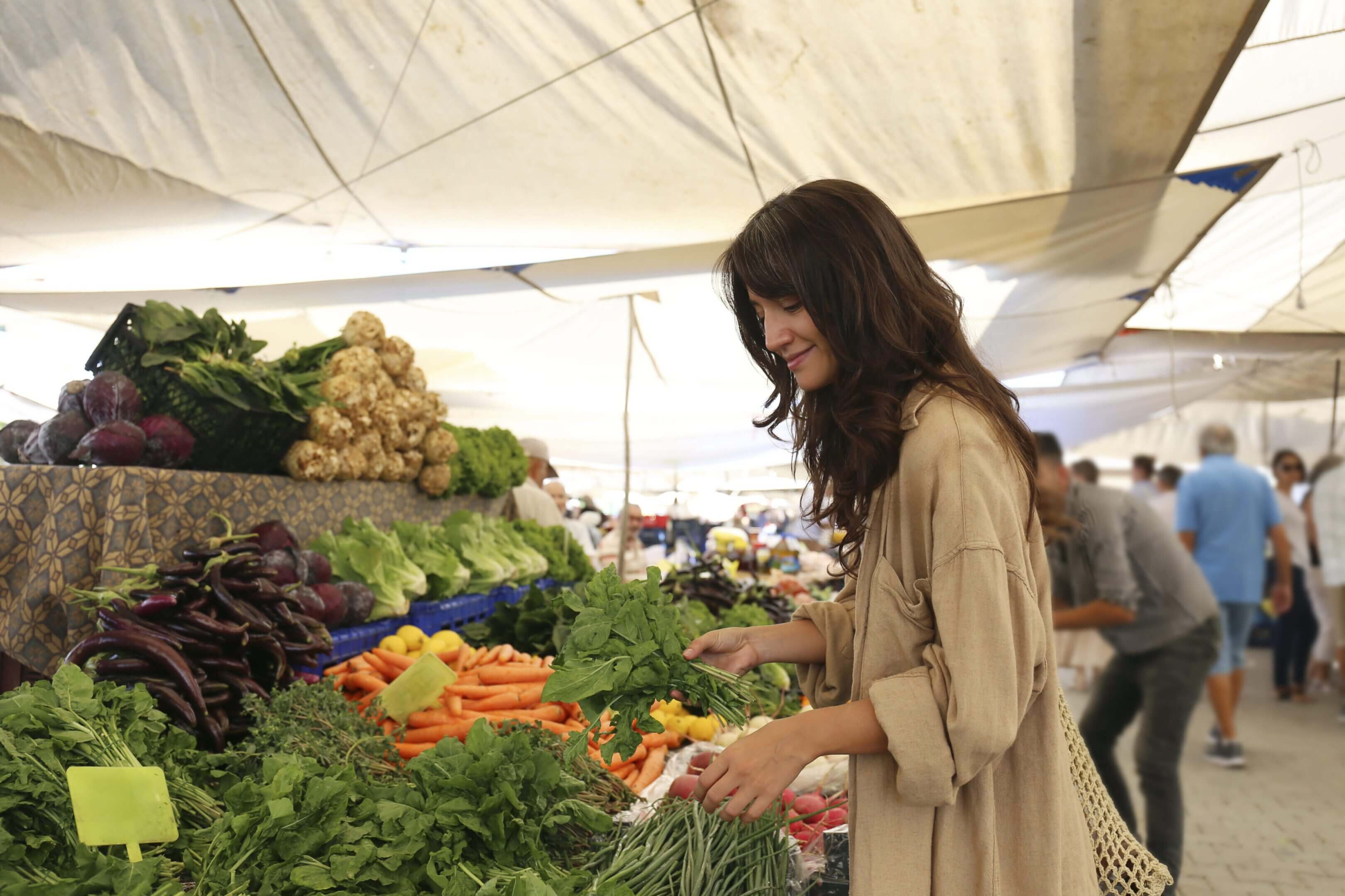 A woman shopping for fresh vegetables at an outdoor market.