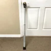 A white cane with a red tip leaning against a door.